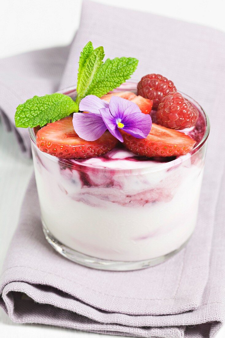 Quark mit roten Sommerbeeren und Veilchen