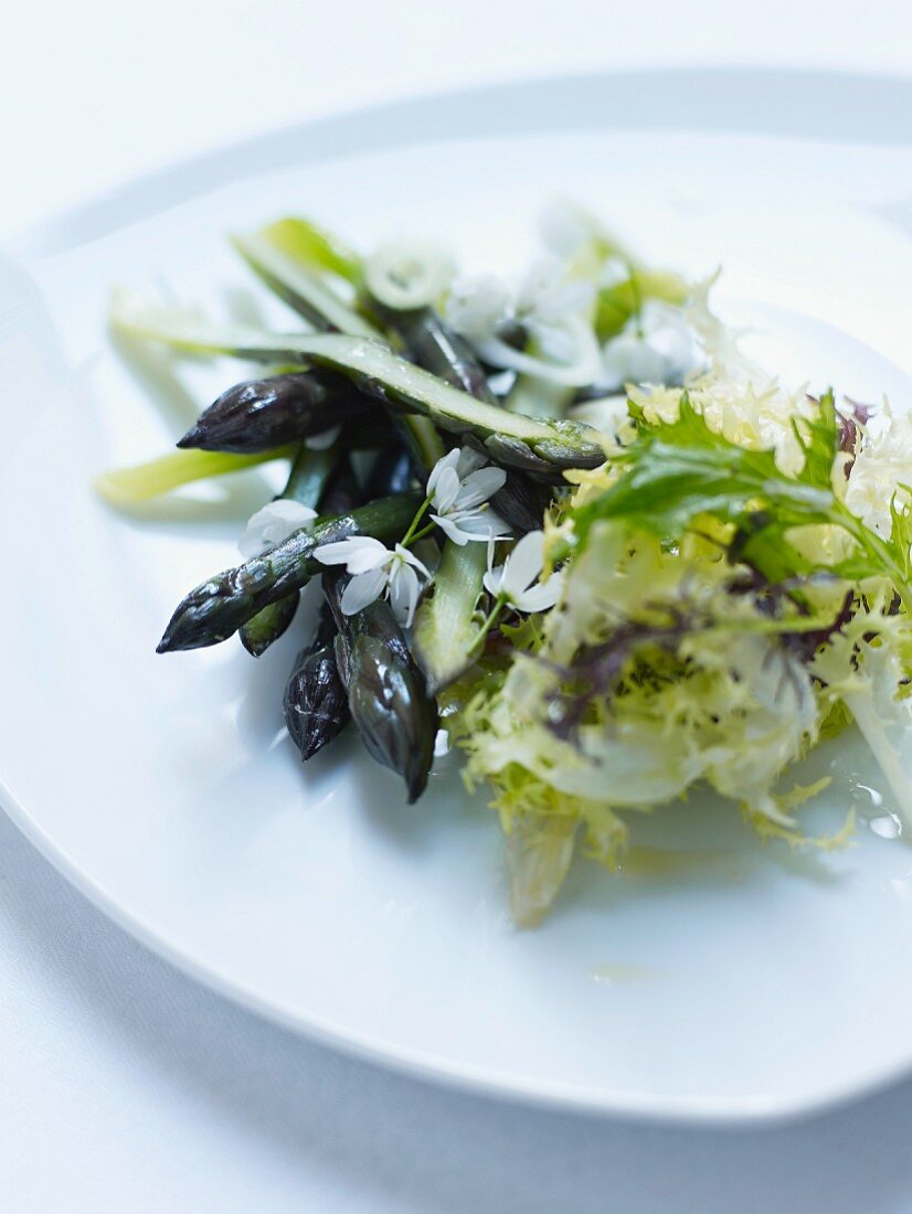 Grüner Spargel mit Blütensalat auf Teller
