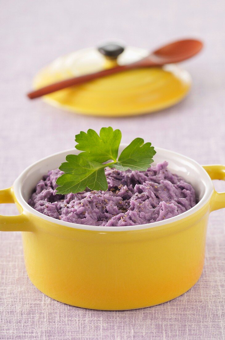 Kartoffelpüree aus violetten Kartoffeln in gelbem Töpfchen