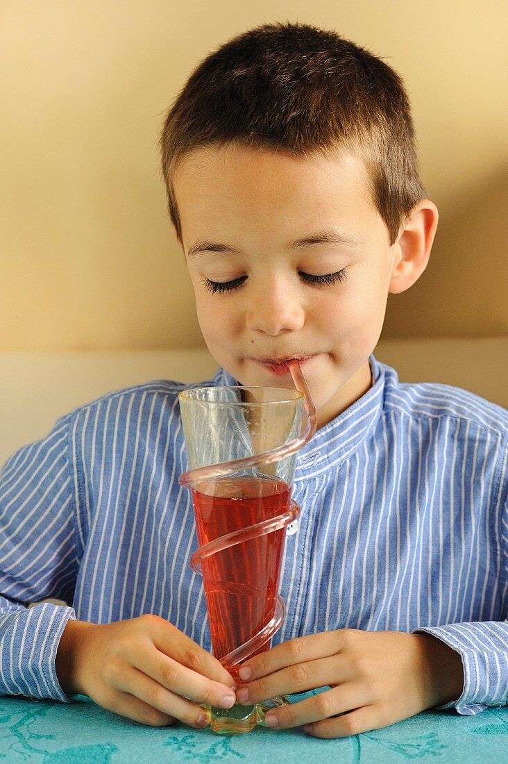 Junge trinkt Erdbeersirup mit Strohhalm