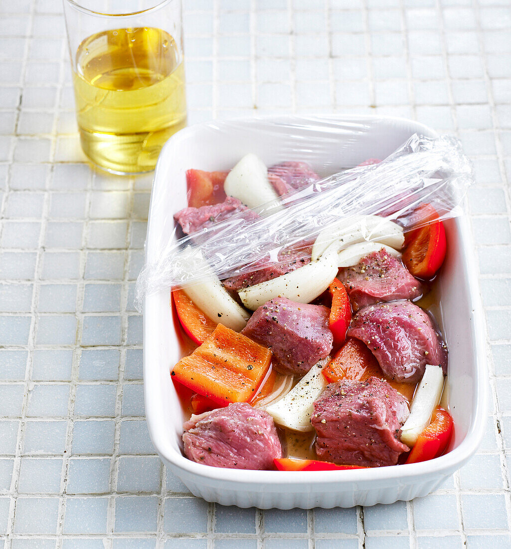 Marinating veal, onions and peppers for shish kebabs