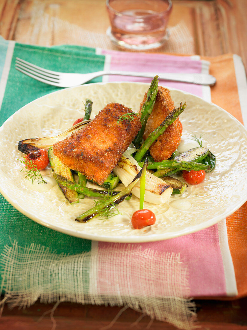 Pieces of breaded salmon with green asparagus, pak-choi cabbage and cherry tomatoes