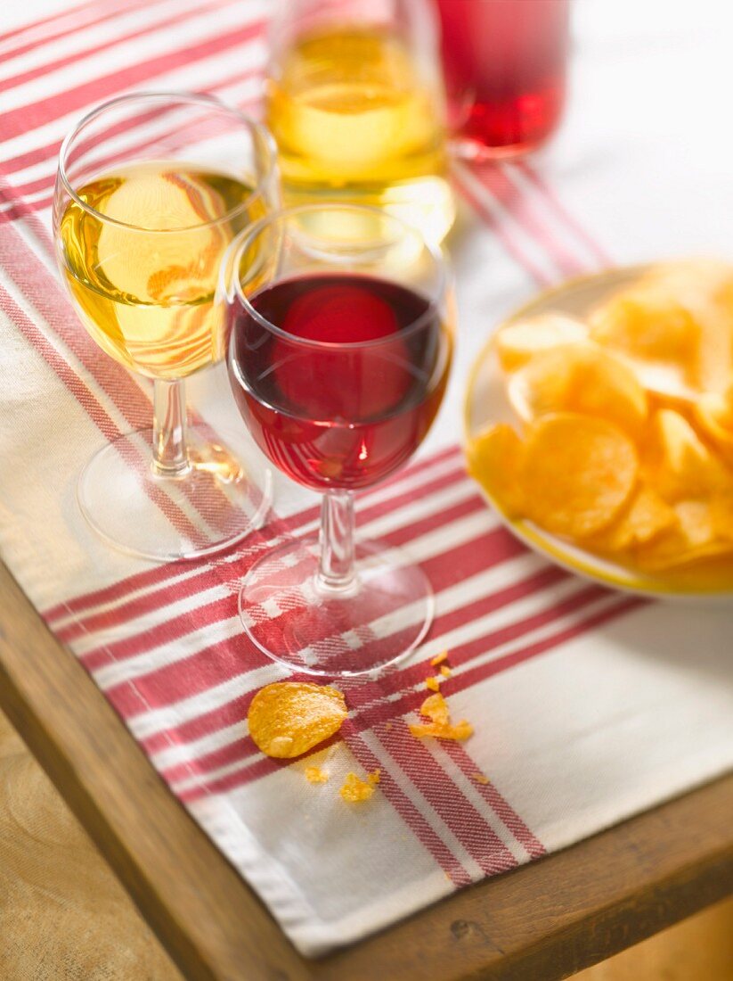 Glasses of red wine with crisps on a table