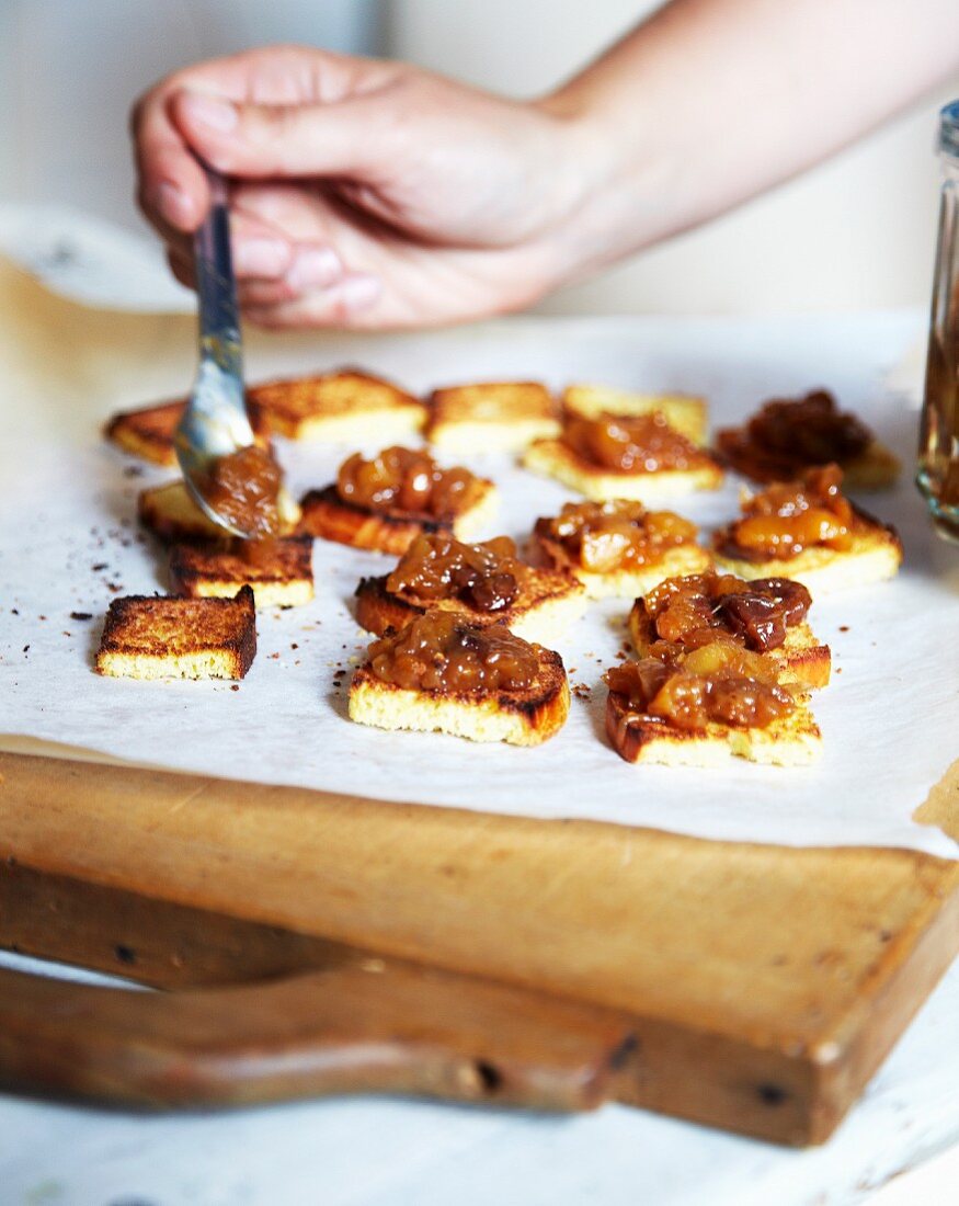 Hände verteilen mit einem Löffel Foie Gras auf Toastbrot