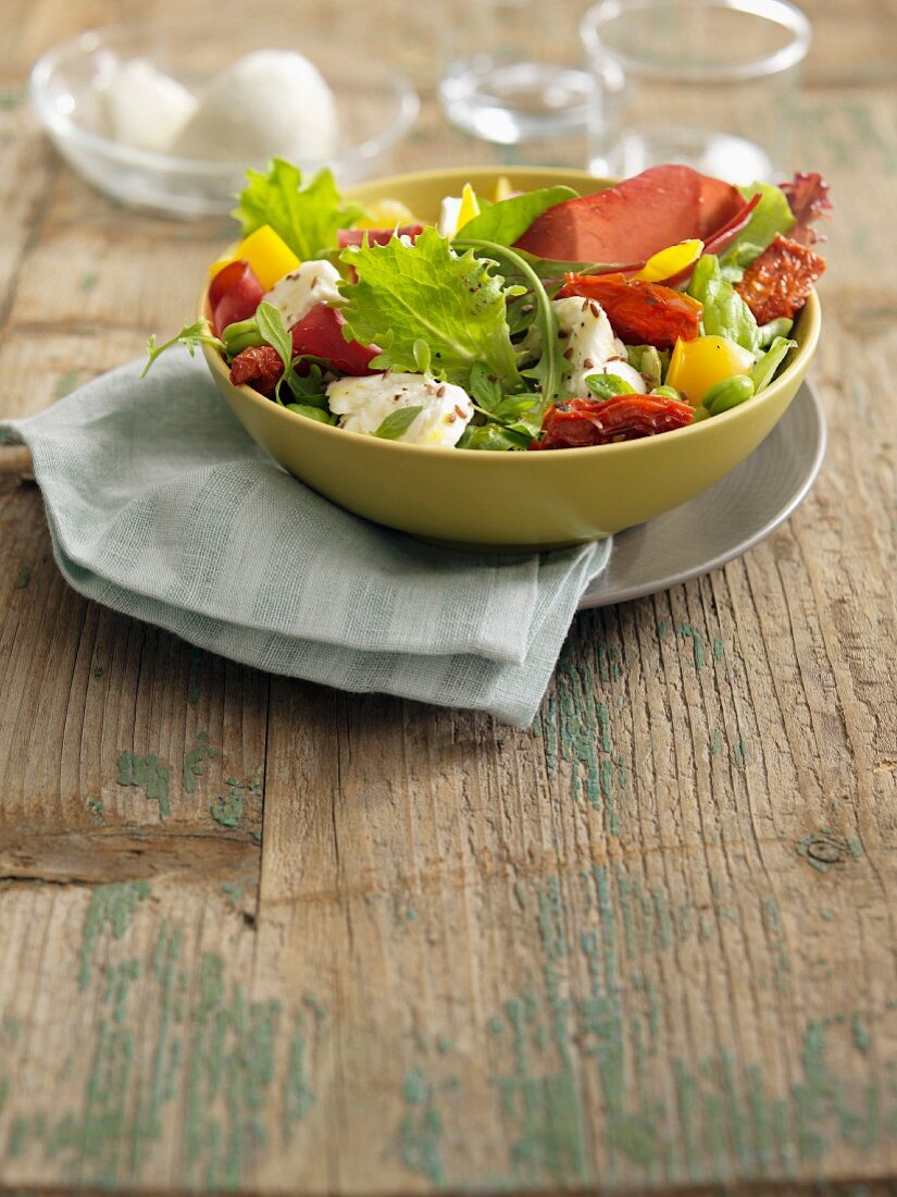 Salat mit gelben Paprika, eingelegten Tomaten, Mozzarella und Bressaola