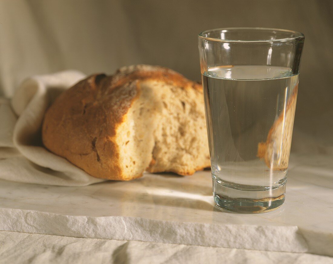 A Loaf of Torn Bread and a Glass of Water