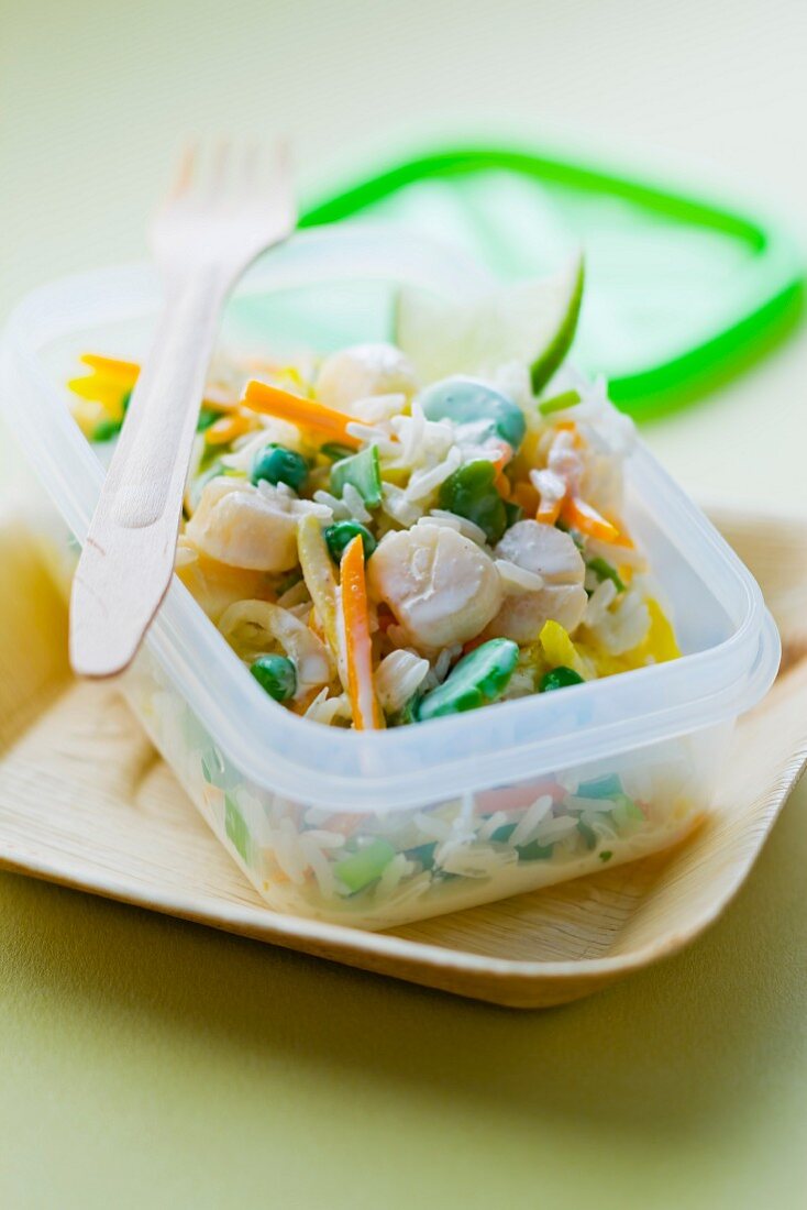 Reissalat mit Jakobsmuscheln im Plastikbehälter zum Mitnehmen