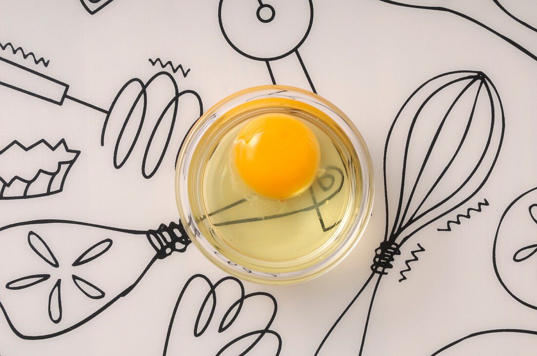 Broken egg in a bowl on a decorated surface