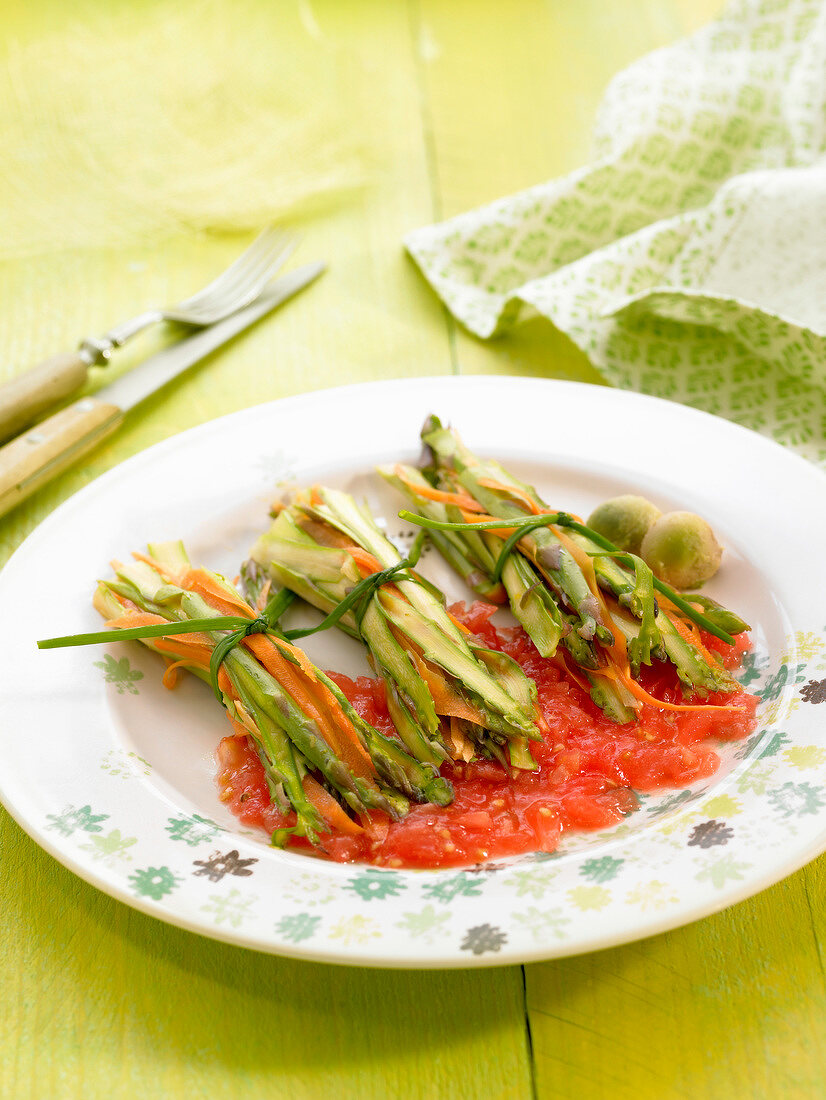 Small bundles of sliced asparagus and carrots with tomato sauce