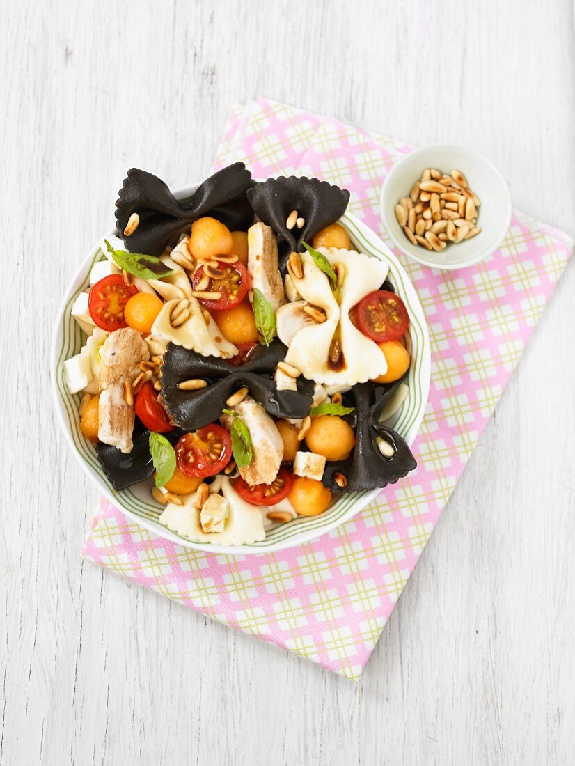 Black and white pasta salad with chicken, cherry tomatoes and melon balls