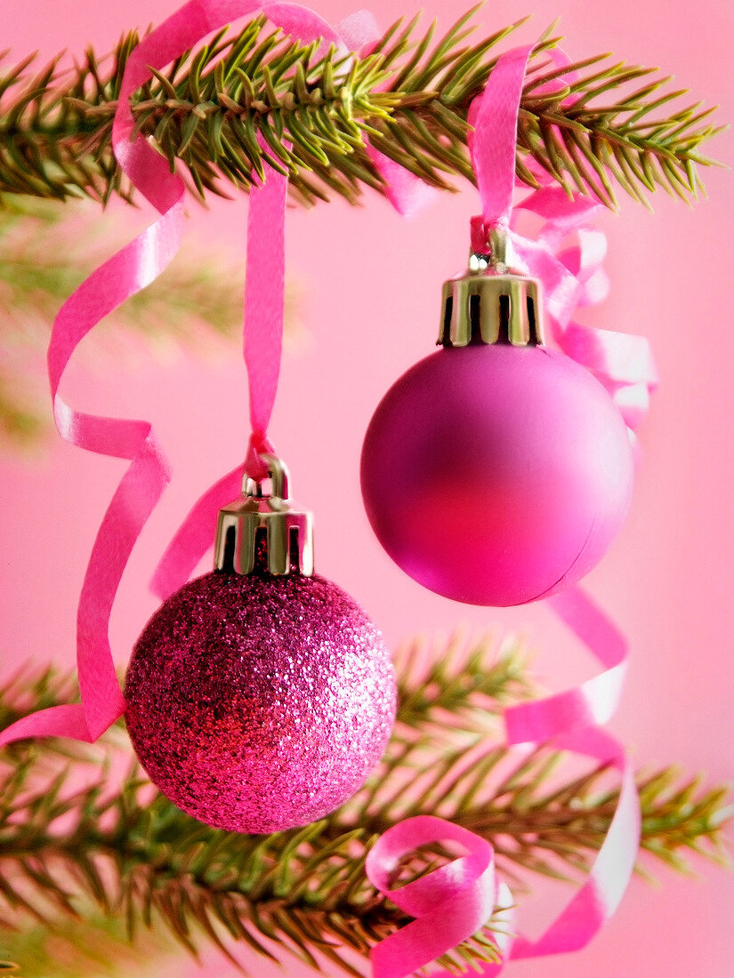 Pinkfarbene Christbaumkugeln hängen am Weihnachtsbaum
