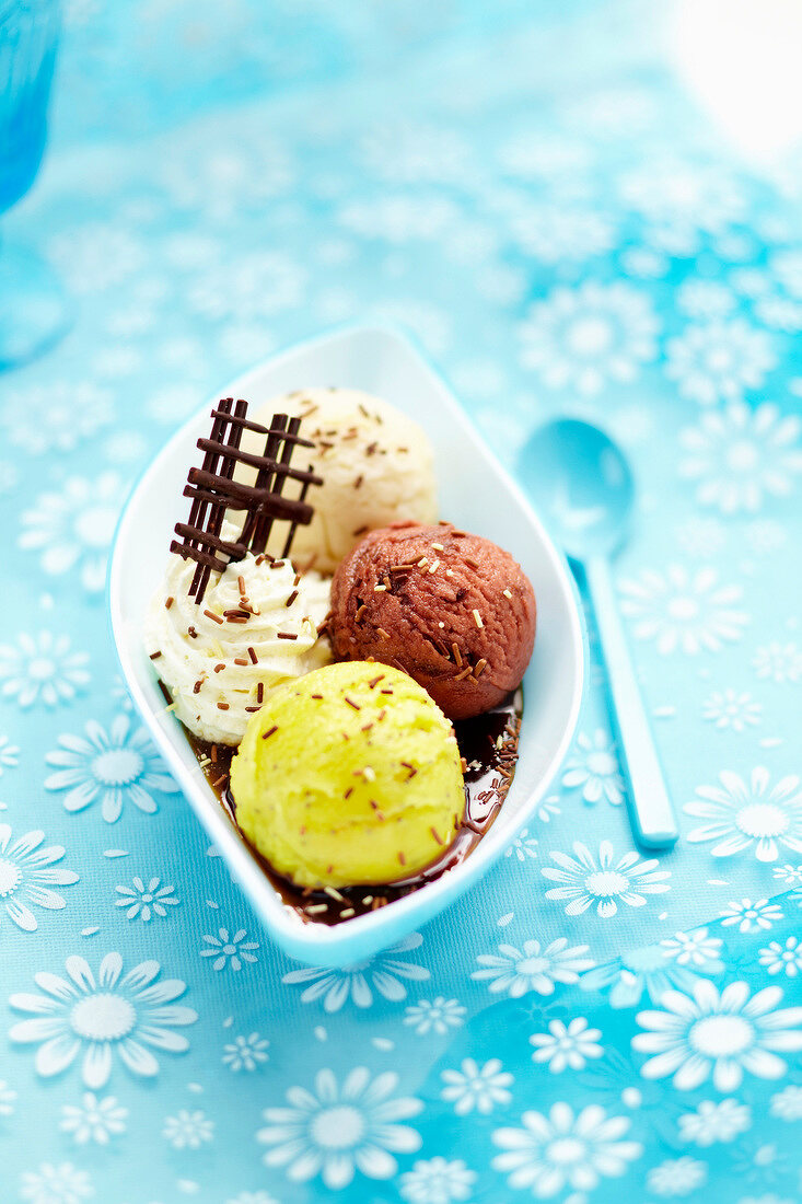 Three-different flavored ice cream scoops with whipped cream