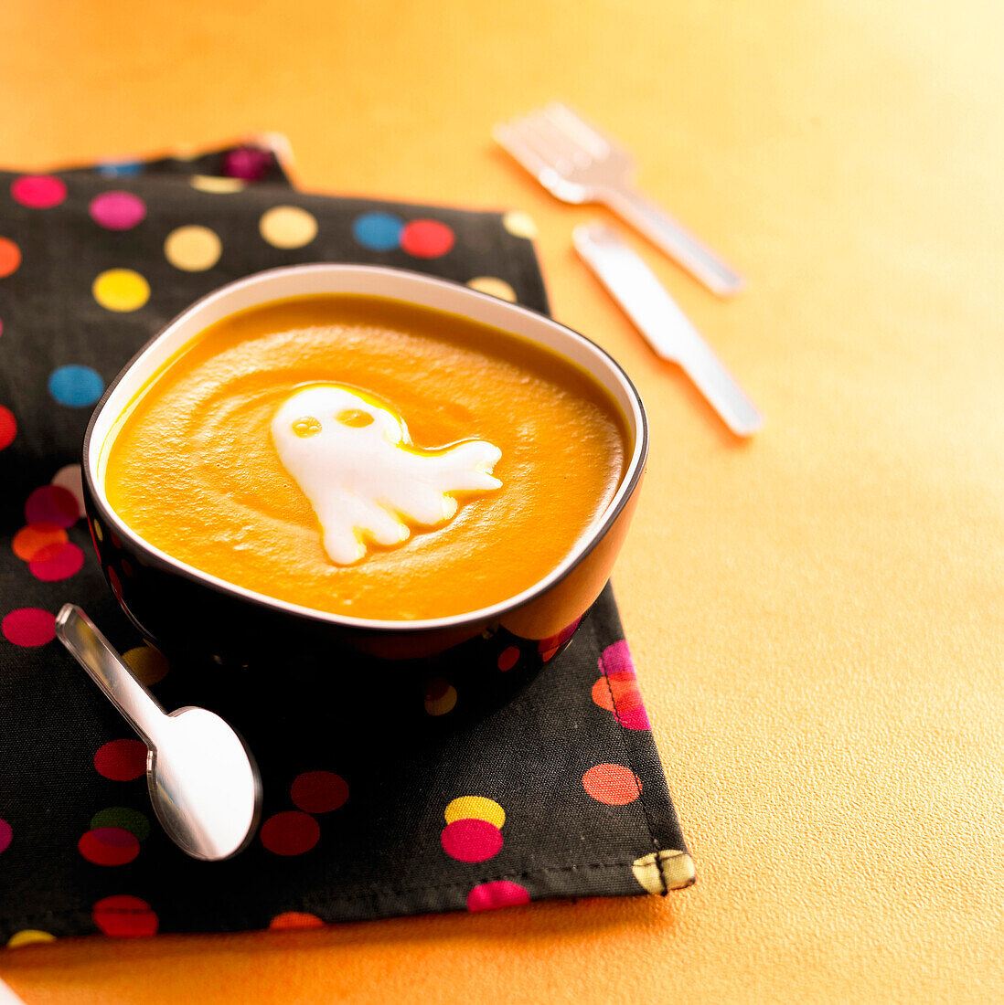 Cream of pumpkin soup with Halloween ghost-shaped whipped cream