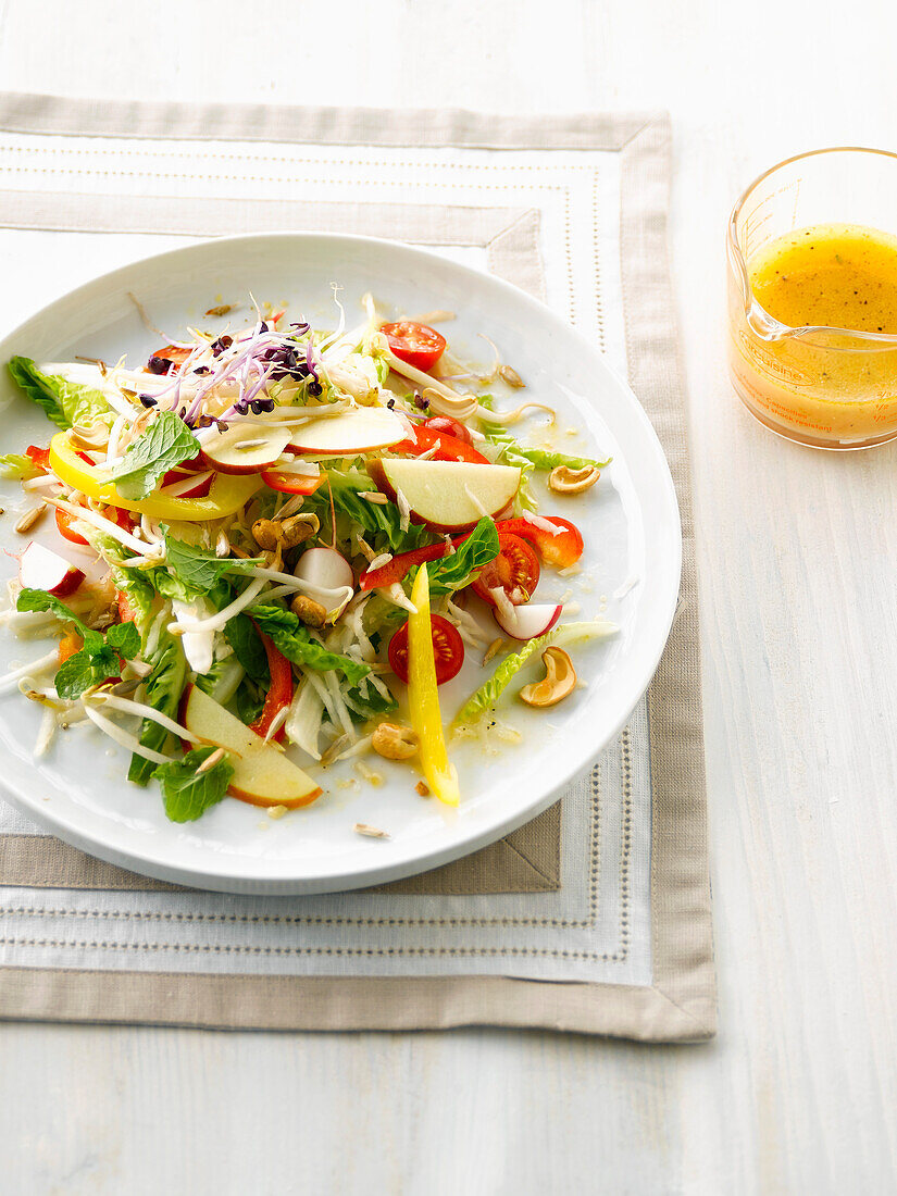 Salat mit Radieschen, Apfel, Cocktailtomaten, Cashewkernen und fruchtigem Dressing