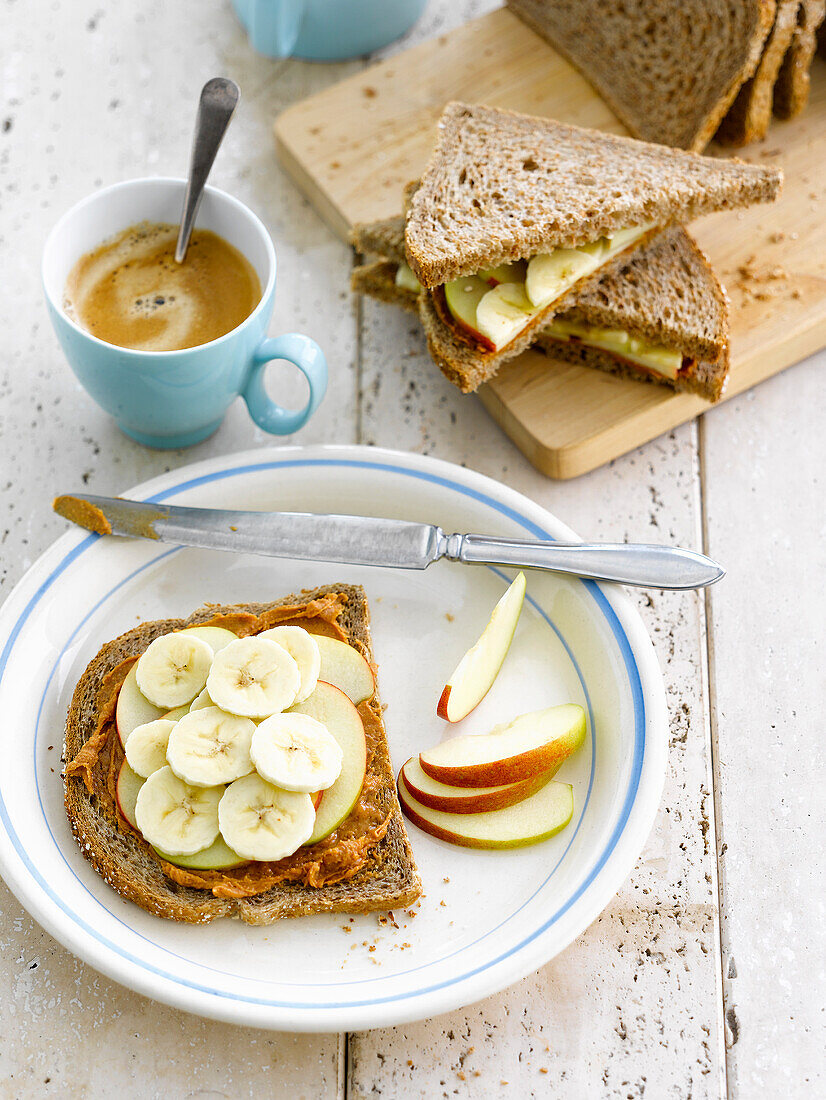 Sliced brown bread with peanut butter,sliced apples and bananas