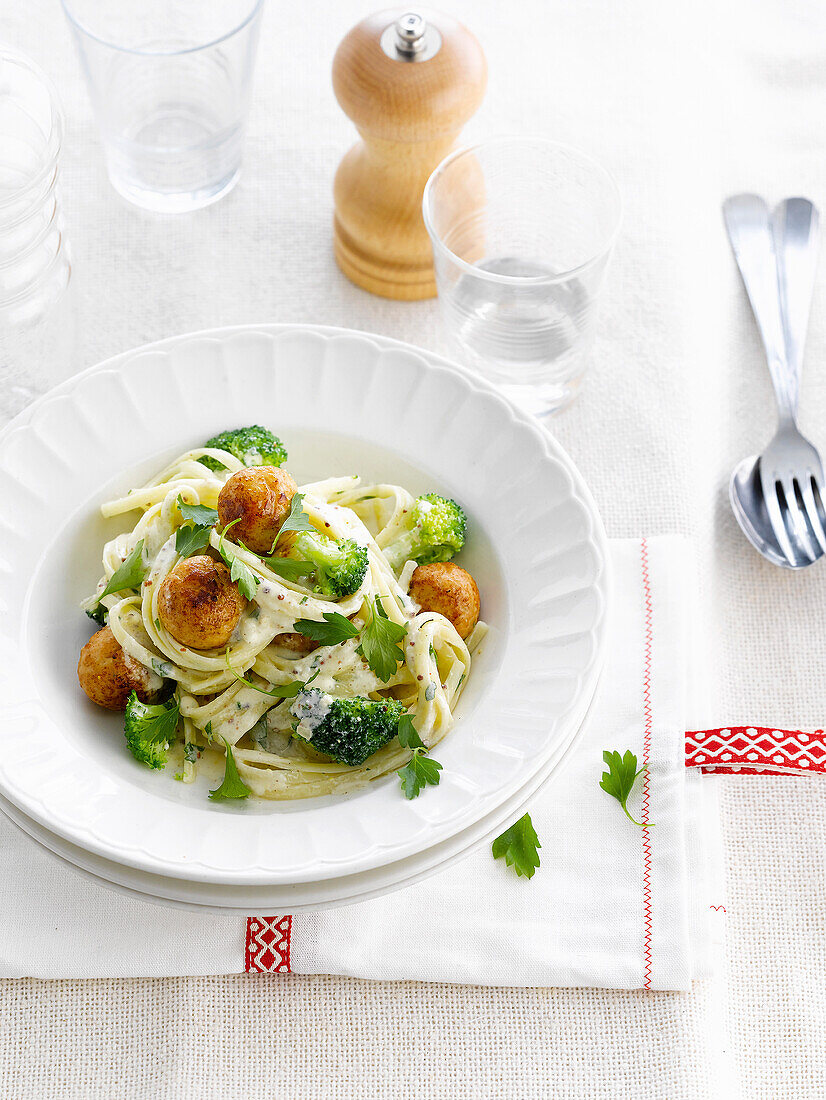 Pasta in creamy sauce with breaded turkey meatballs and broccolis