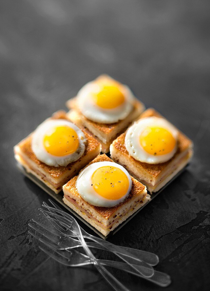 Ham and cheese mini taosted sandwiches topped with fried quail's eggs