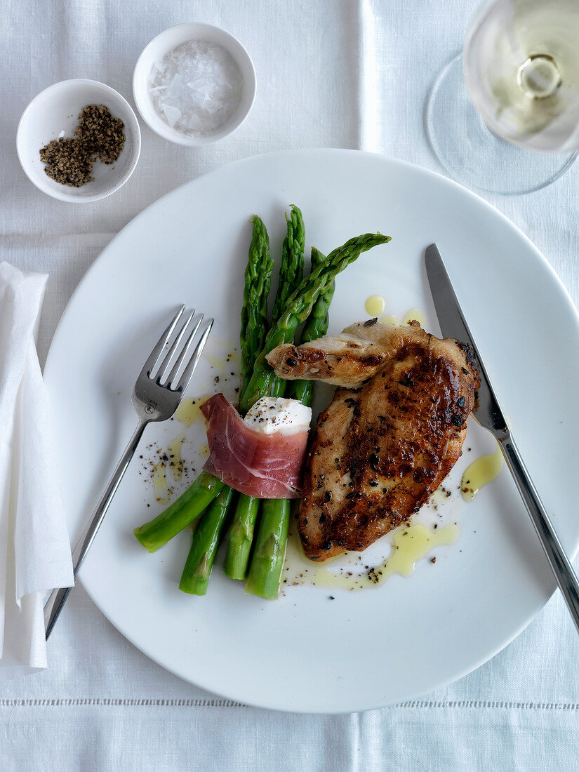 Grilled chicken breast,bundle of green asparagus tied with raw ham and goat's cheese