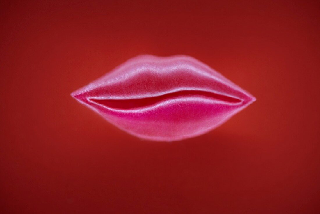 Pinke Lippen aus Zucker auf rotem Untergrund
