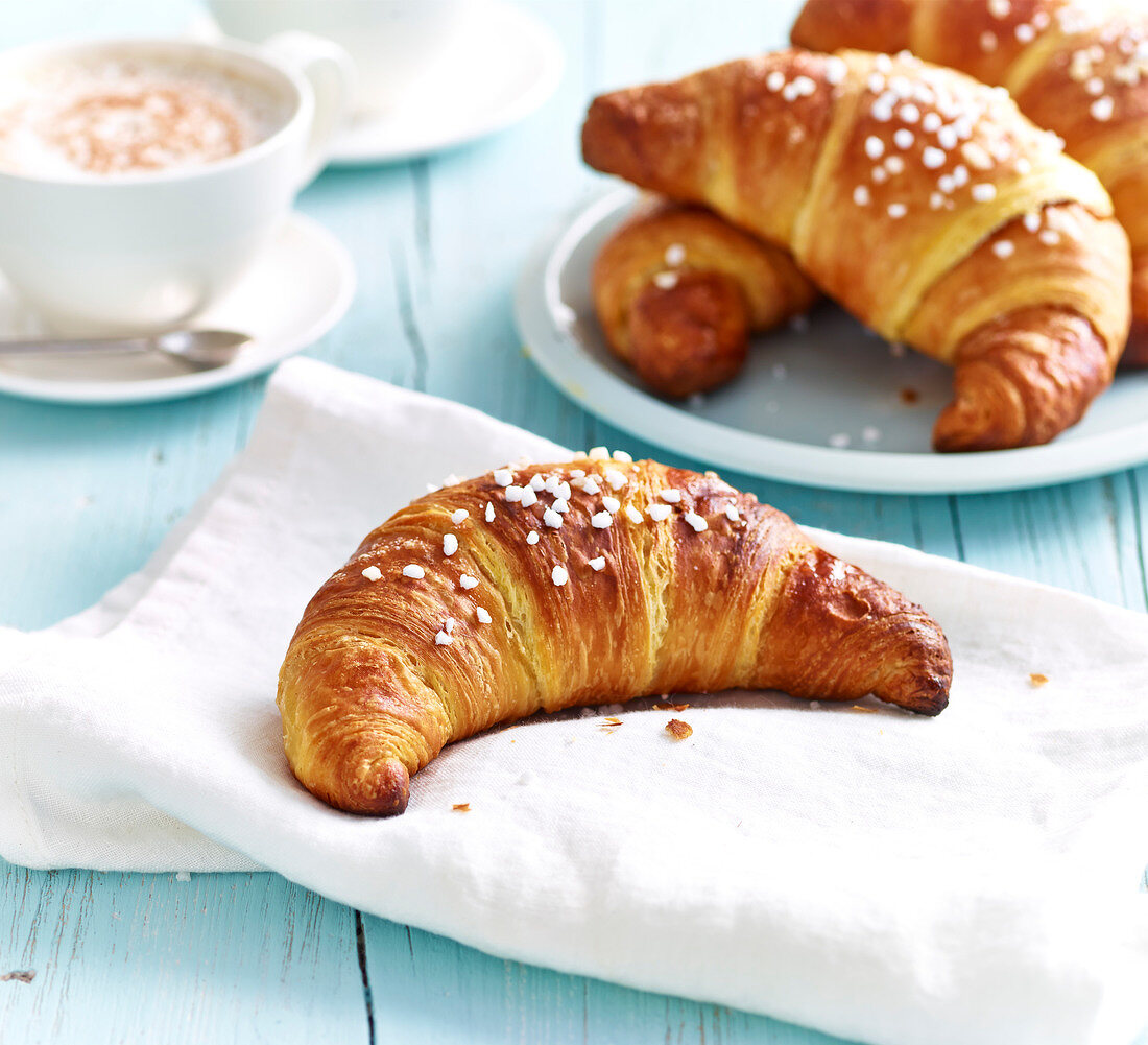 Croissants sprinkled with crystallized sugar and a cup of cappuccino