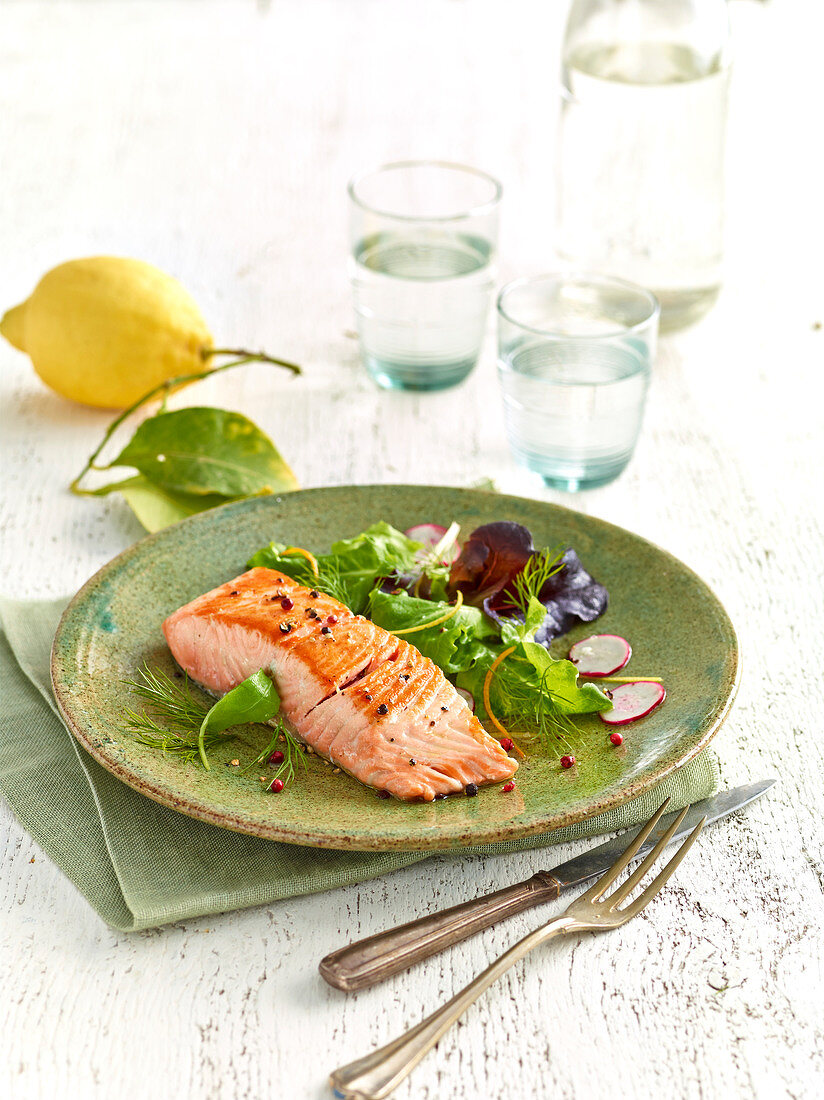 Piece of grilled salmon and mixed salad with orange zests