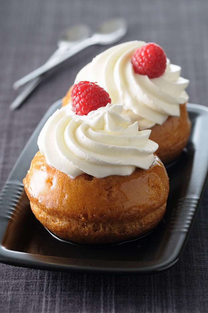 Zwei Baba au rhum mit Schlagsahne und Himbeere