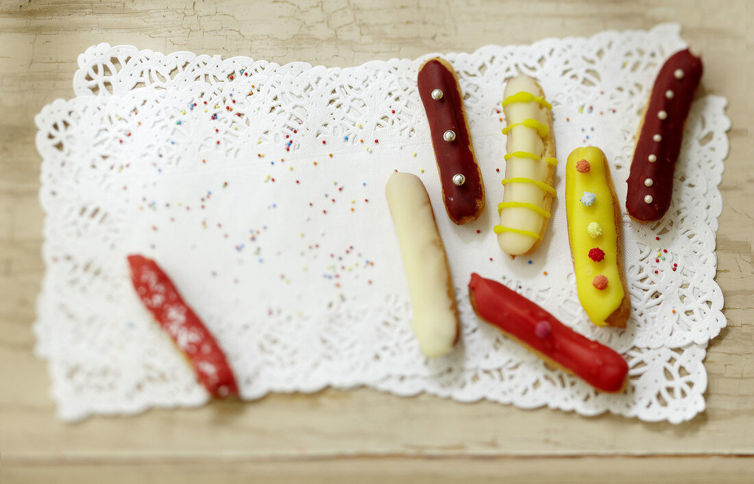 Verschieden verzierte Mini-Eclairs auf Tortenspitze