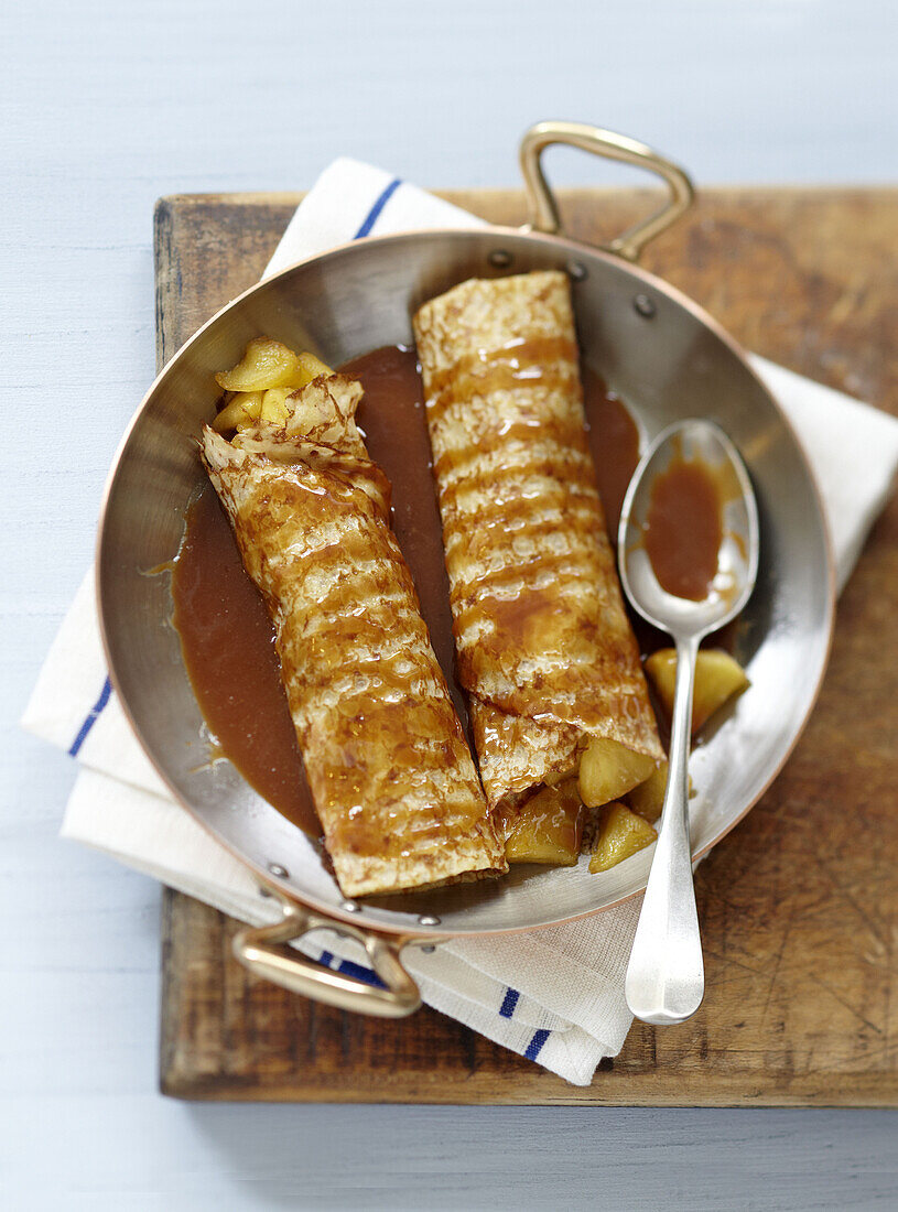 Rolled crepes garnished with apples and salted butter toffee sauce