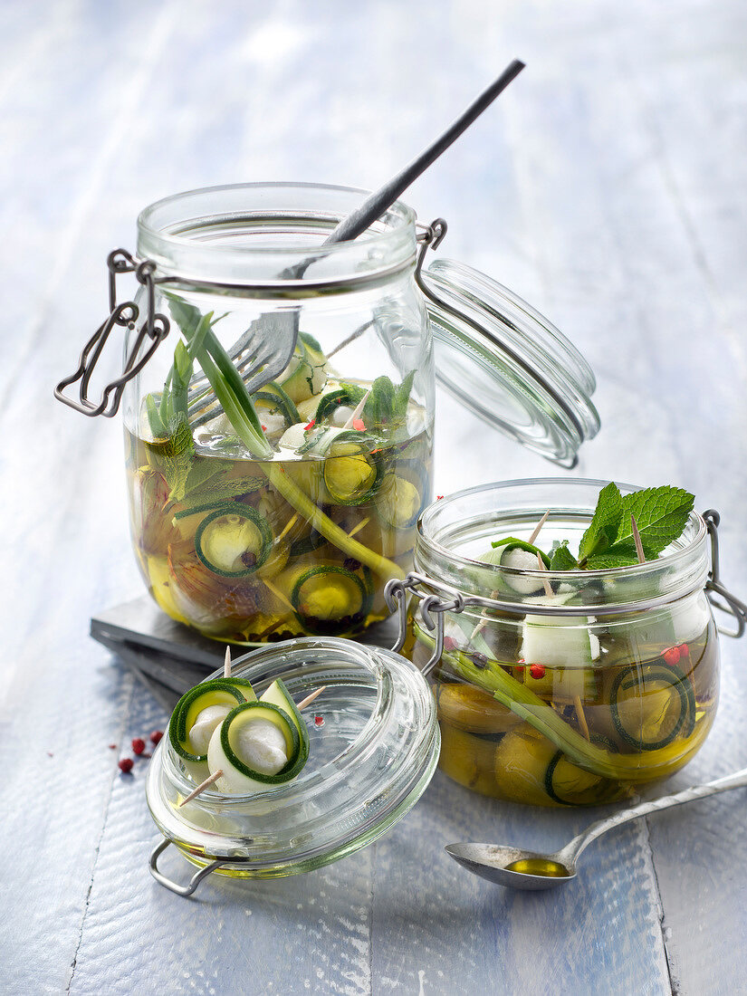 Jars of zucchinis and mozzarella marinated in oil with spring onions and mint
