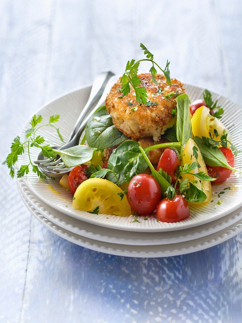 Salat mit roten und gelben Kirschtomaten, Babyspinat und Fischfrikadelle