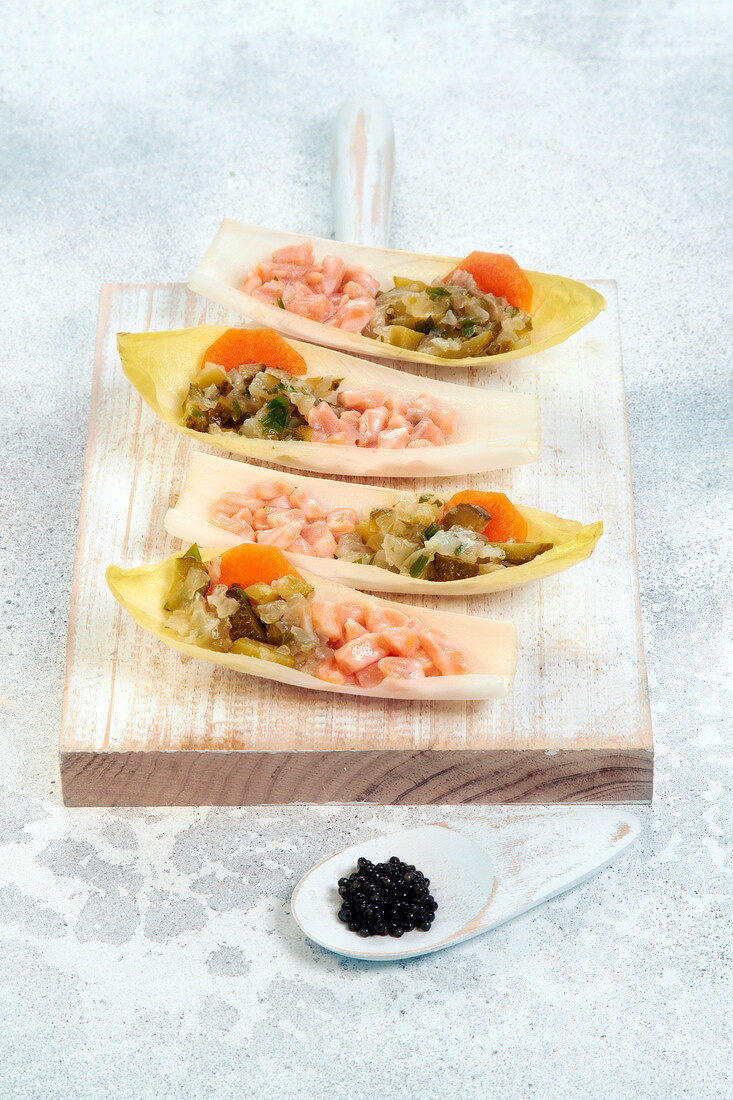 Chicory boats garnished with marinated salmon, pickles and carrots
