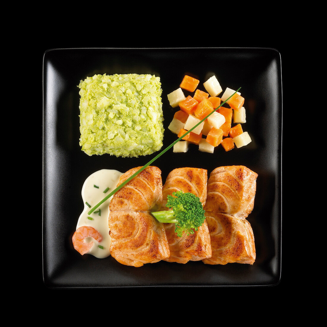 Gebratener Lachs mit Gemüse und grünem Püree auf einem schwarzen Teller
