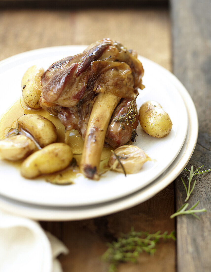 Confit lamb knuckle joint with garlic and potatoes with rosemary
