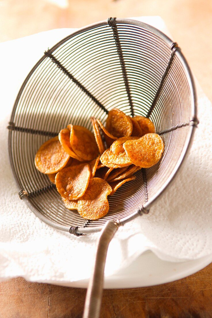 Frittierte Kartoffelchips auf Küchenkrepp zum Abtropfen geben