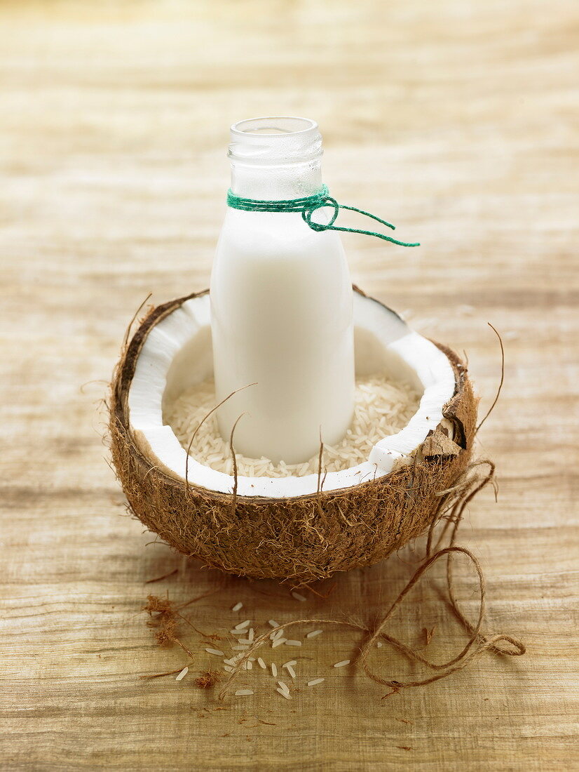 Bottle of coconut milk in a coconut shell and rice