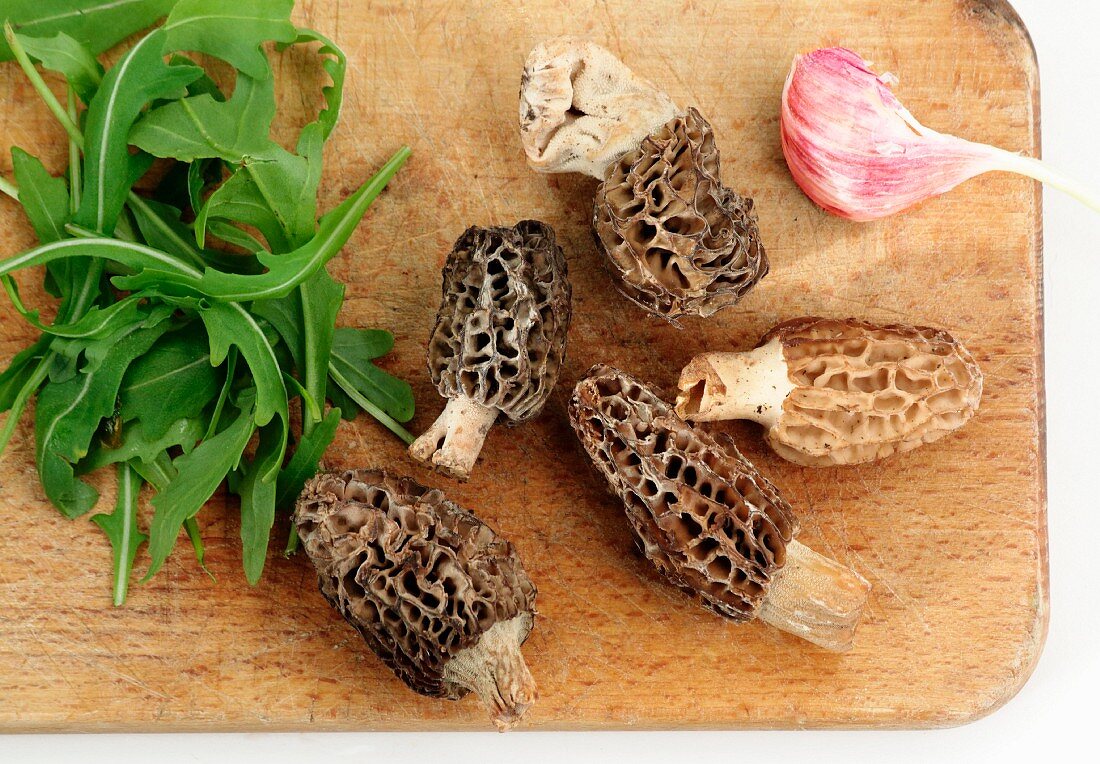 Rocket lettuce,morels and garlic on a chopping board