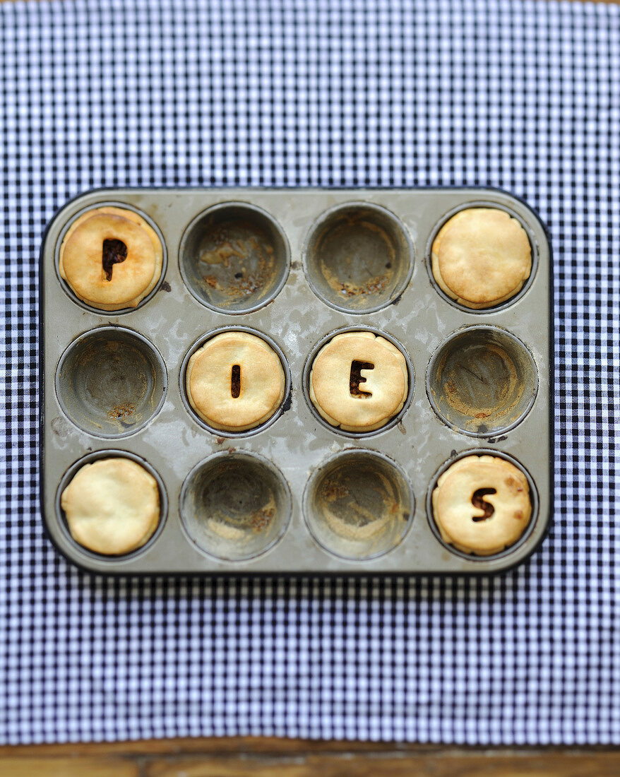 "The word ""pies"" written on small pies in a baking mould"
