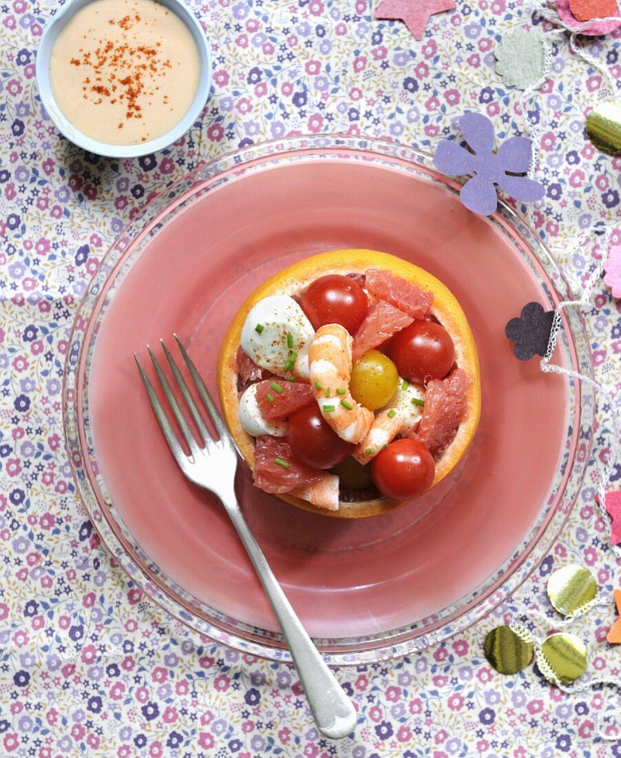 Salat mit Kirschtomaten, Garnelen, Mozzarellabällchen und Grapefruit in Grapefruithälfte