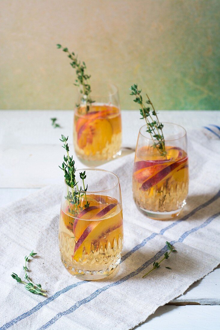 Sangria mit Pfirsich und Thymian in Gläsern