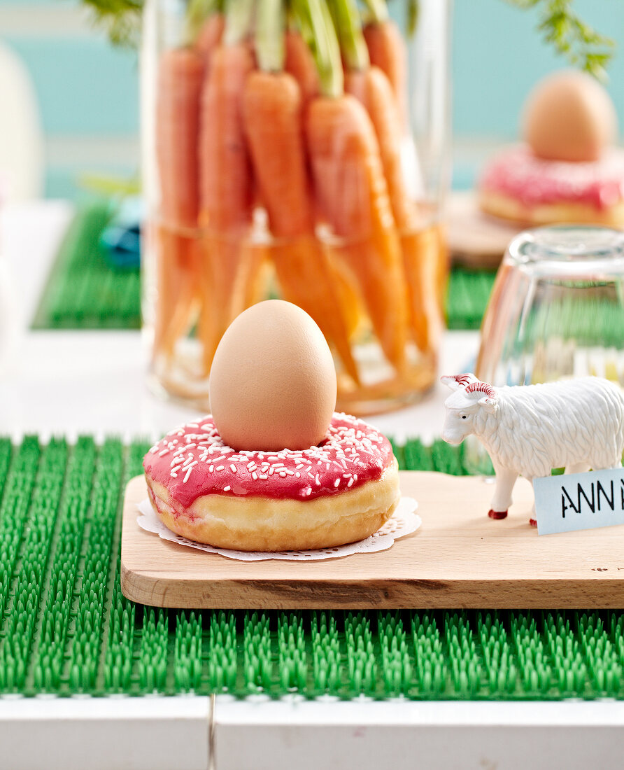 Donut topped with an egg,figurine name-tag,bunch of carrots in a jar of water