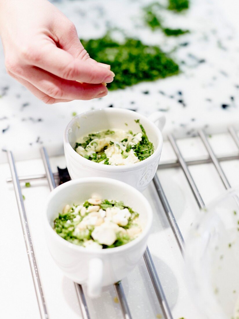 A hand sprinkling parsley into bowls