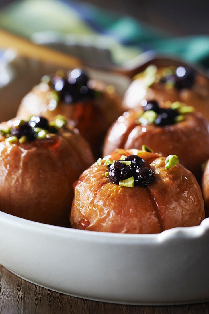 Baked apples garnished with crushed pistachios and macerated blackcurrants