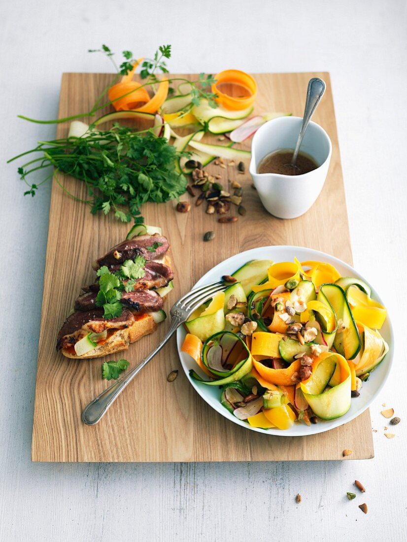 Thin strips of zucchinis and carrots with dried fruit and seeds, duck magret on toast