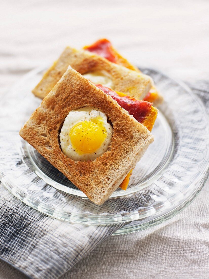 Ham and cheese toasted sandwich topped with a fried quail's egg