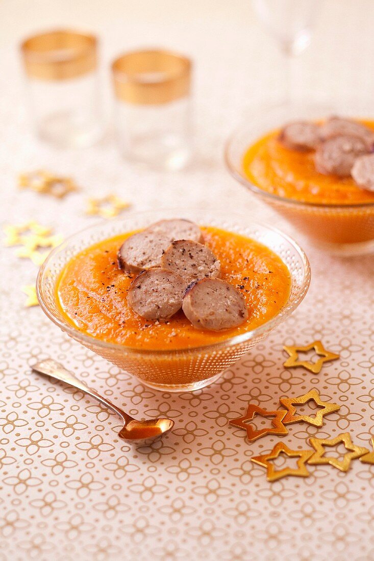 Butternut squash and carrot pureed soup with grilled and sliced white blood sausage