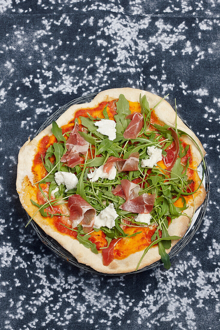 Pizza with cured ham, mozzarella di bufala and rocket salad