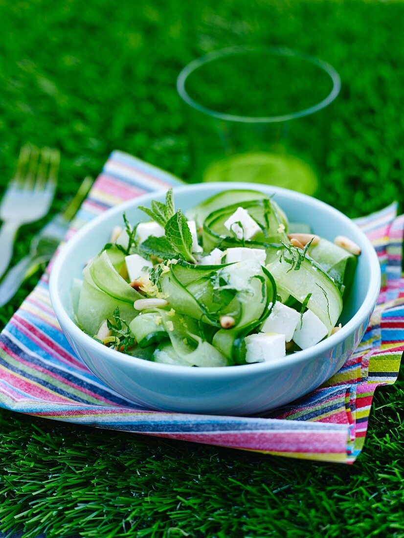 Salat mit Gurkenstreifen, Fetawürfeln, Minze und Pinienkernen