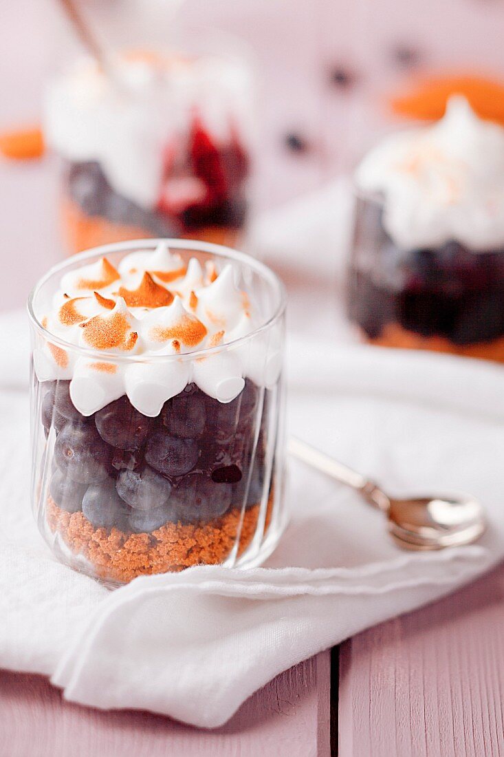 Gingerbread and blueberry dessert with meringue in glasses