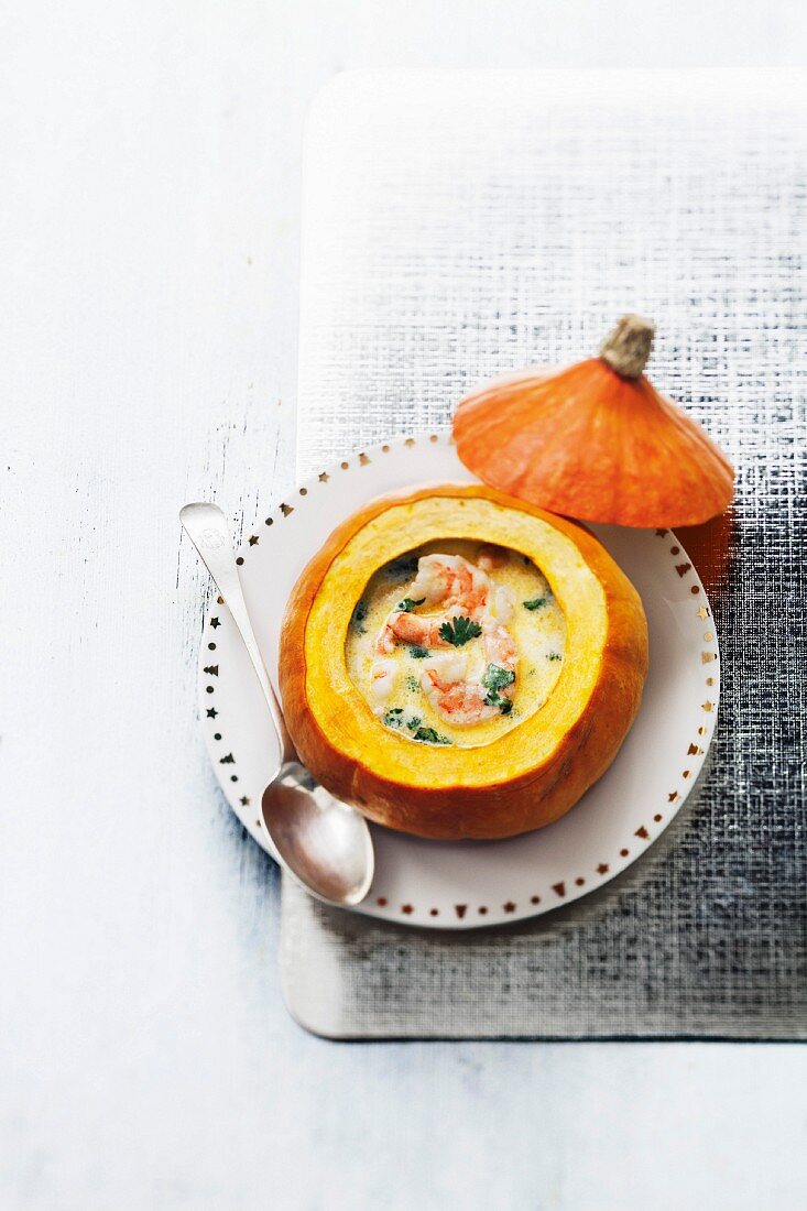Cream of pumpkin soup with shrimps served in a pumpkin shell