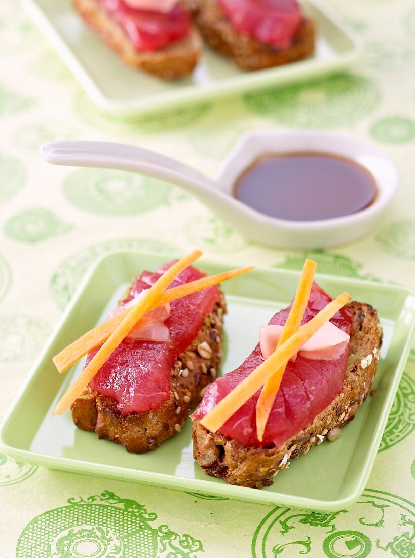 Geröstetes Kornbrot mit rohem Thunfisch, Ingwer und Karottenstäbchen, nach Art von Sushi